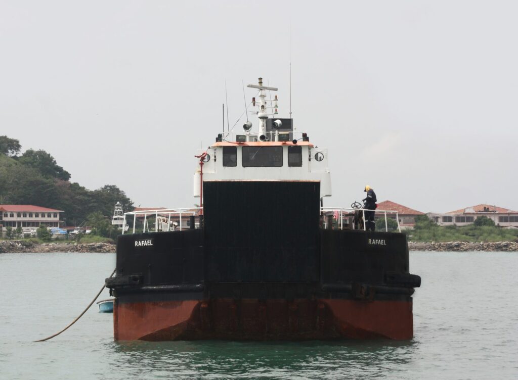 The landing craft RAFAEL bow on with its ramp raised and a crew member in full PPE working the winch